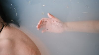A photograph of a hand in a bathtub of water