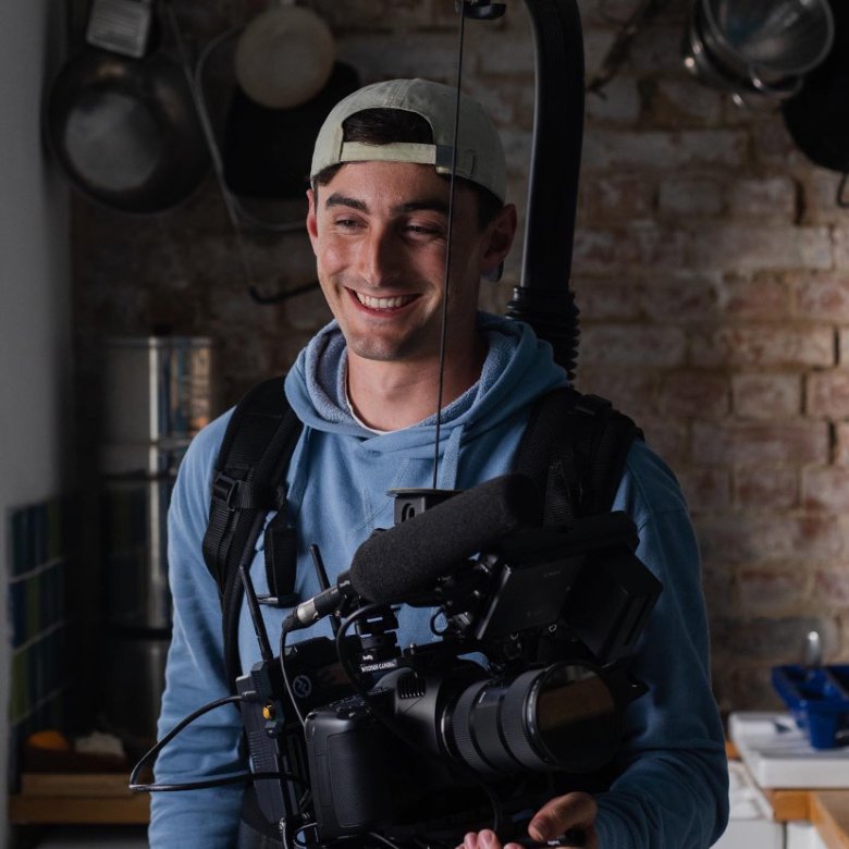 A young man in a backwards cap holding a large camera