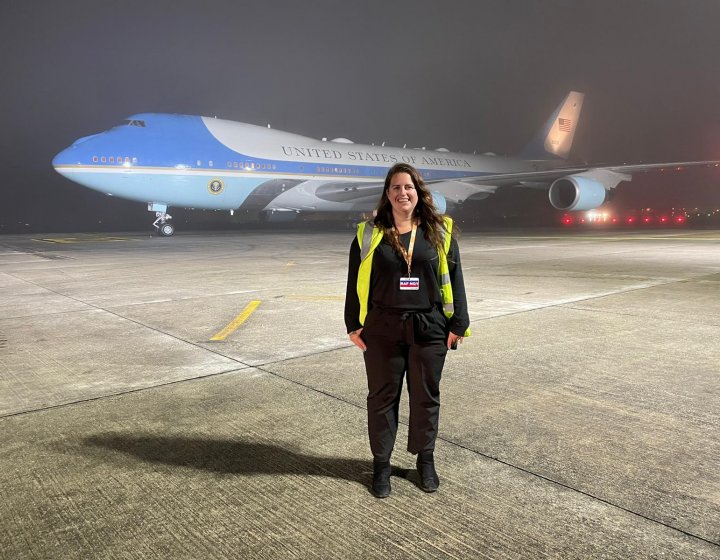 Sustainable Tourism Management wearing a high vis jacket, standing in front of a plane
