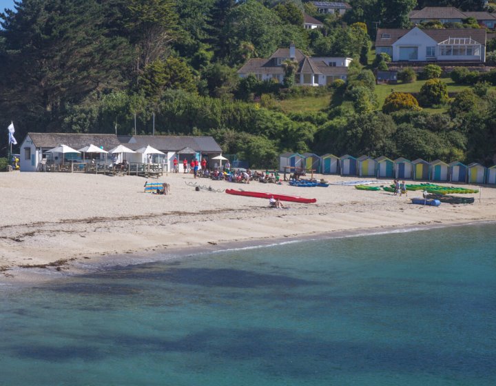 Swanpool Beach from the water with the beach, cafe and beach huts in the background