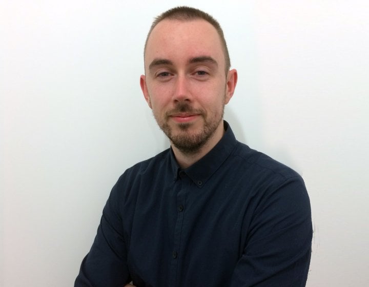 A headshot of Dr John Finnegan sat against a white wall