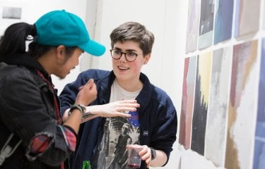 Two Falmouth University students discussing images at an exhibition.