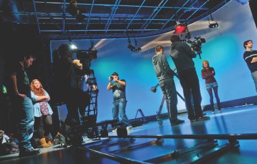 Students working in television studio lit up in blue at Falmouth University