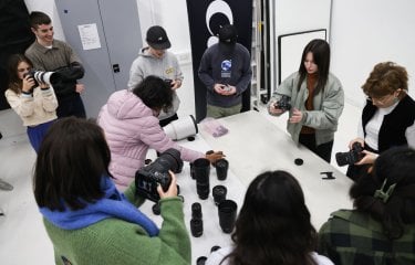 A group of students stood around a white table looking at camera equipment