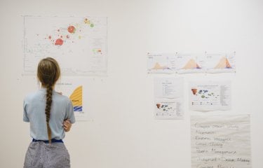 A girl looking at print outs of business graphs on a wall