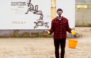 Sustainable Product Design graduate Niall Jones wearing mask and carrying a bucket on Porthtowan beach as part of SAS Floater campaign. 