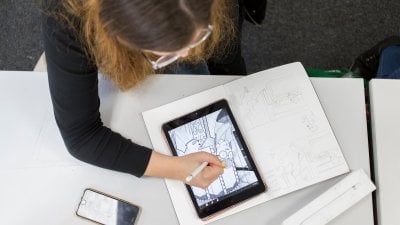 A birds-eye view image of a girl drawing on a tablet computer