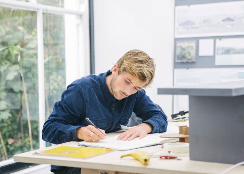 Falmouth University Architecture student working at a desk, wearing a blue shirt