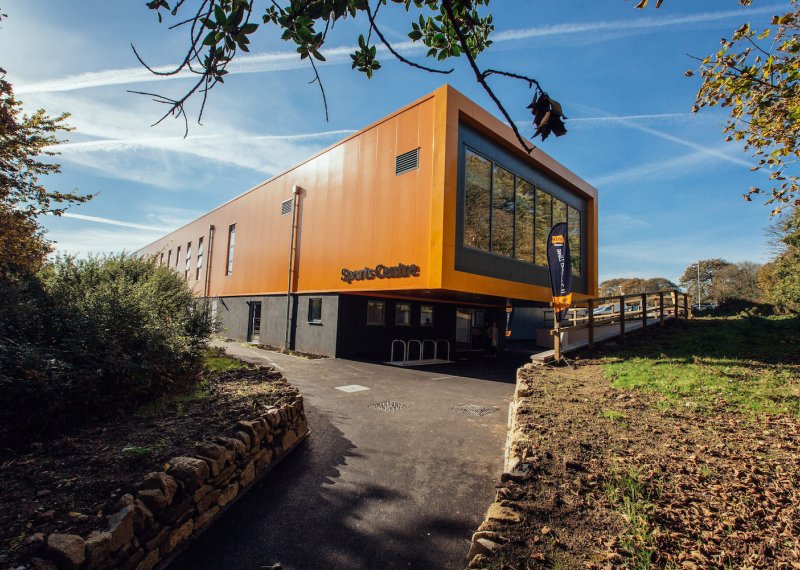 Falmouth University Sports Centre building exterior with blue sky and a path