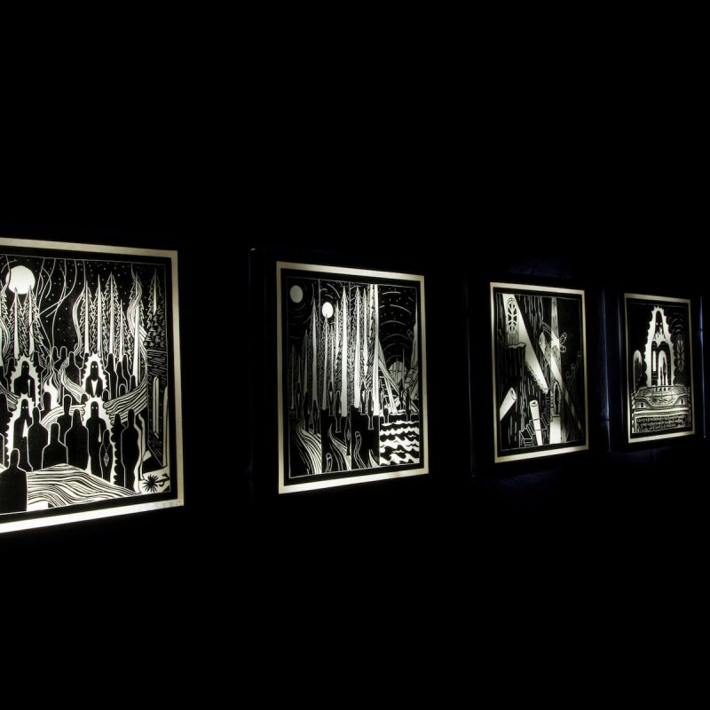 Set of monochrome, illustrated artworks displayed on black wall.