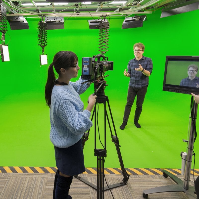 Falmouth students working camera and viewing a screen in a green studio.