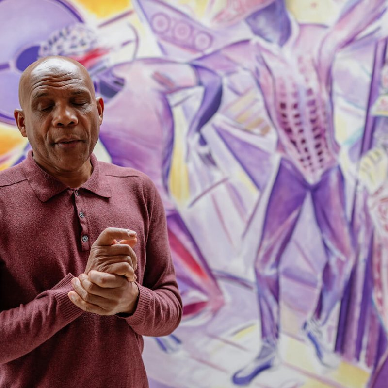 Denzil Forrester with his hands clasped, in his studio