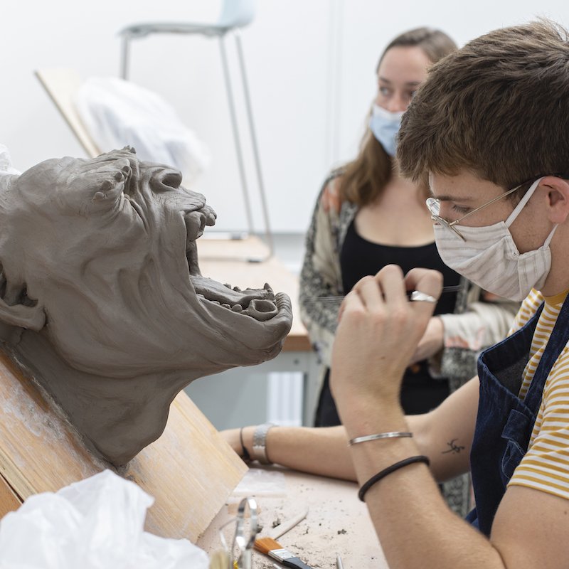 A student working on a model of a clay head screaming