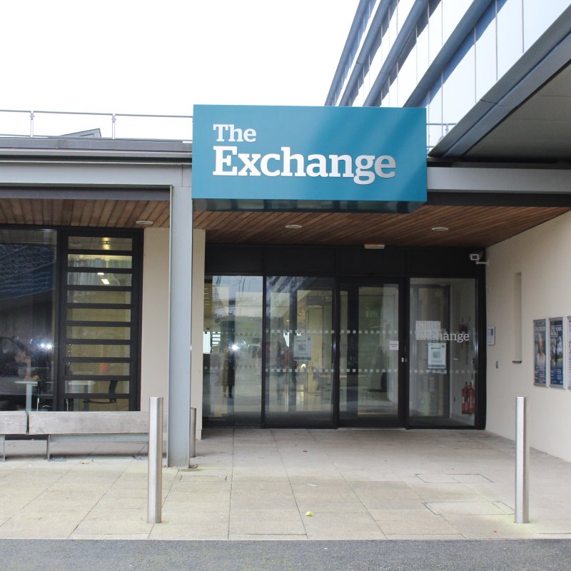 glass fronted building with 'The Exchange' sign on a blue background