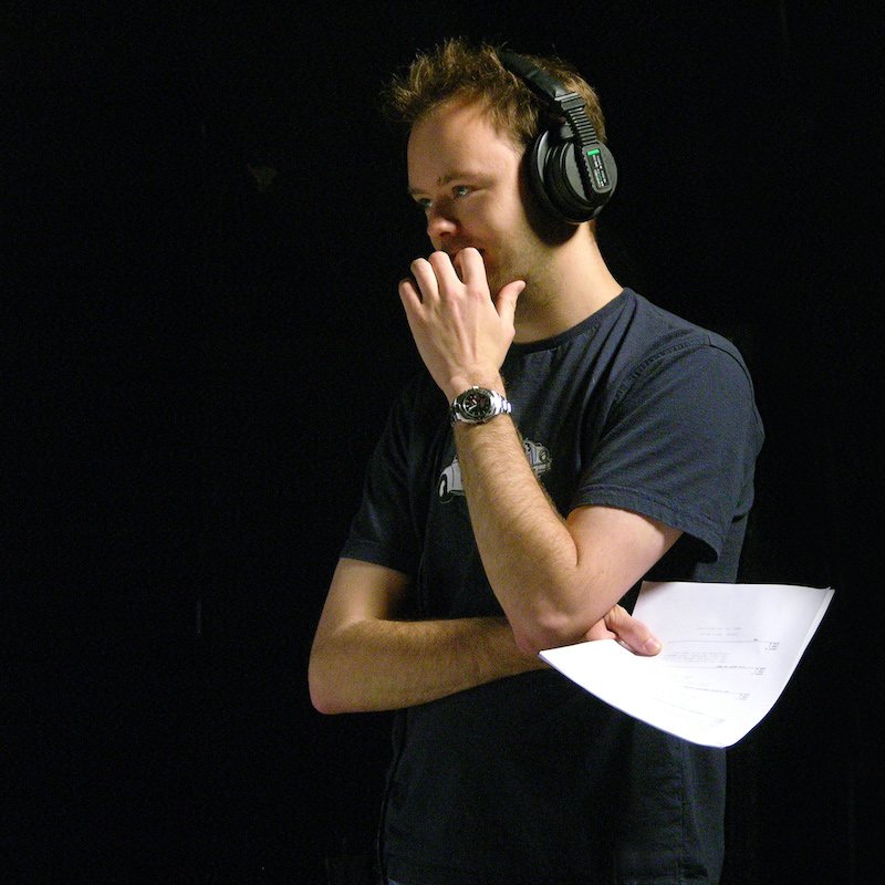 Male student holding paper and wearing headphones.