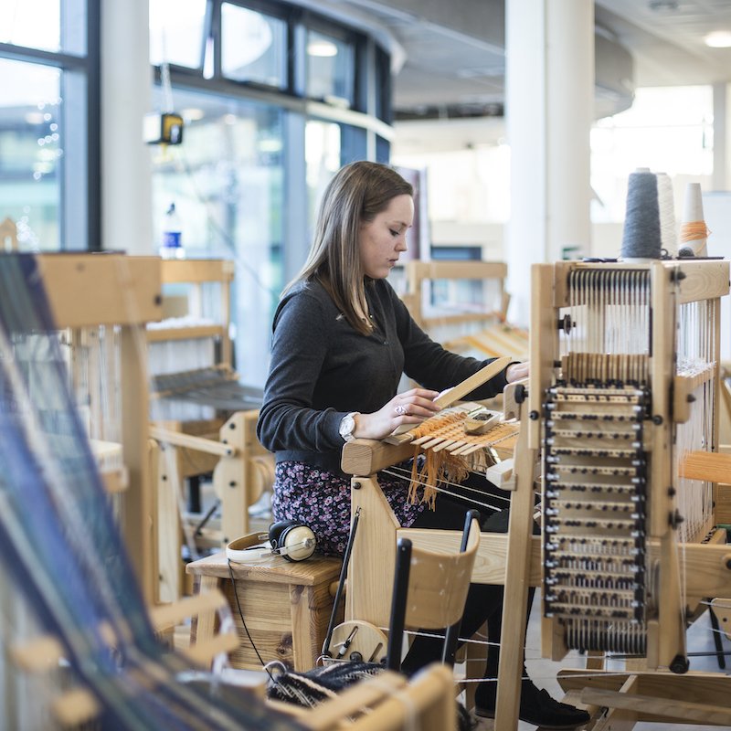 Textiles student working at a loom in a studio