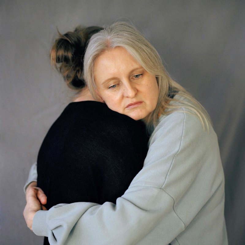 Photography: older woman hugs a younger woman, who isn't hugging back