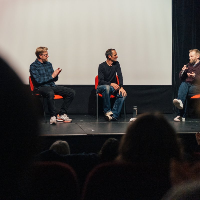 Three men on a stage doing a Q&A with a live audience