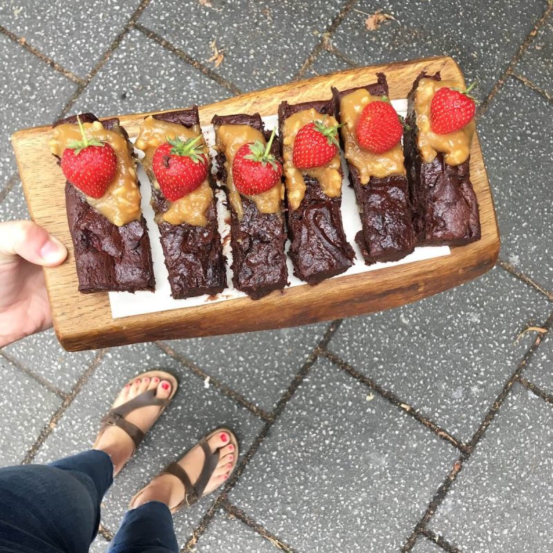 A person holding a tray of chocolate cake slices with a strawberry on top