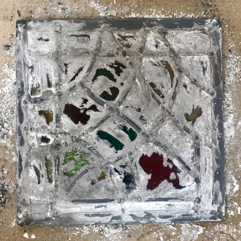 A piece of stained glass on a concrete floor