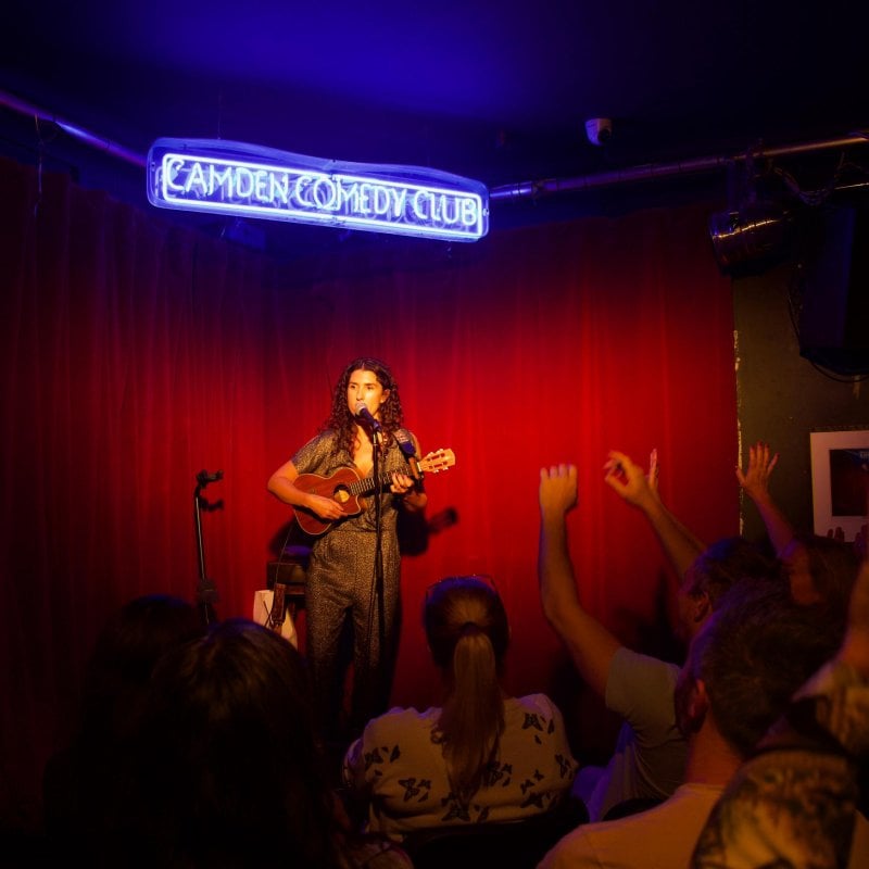 Comedy writing student Kayleigh Jones performing on stage with a ukulele 