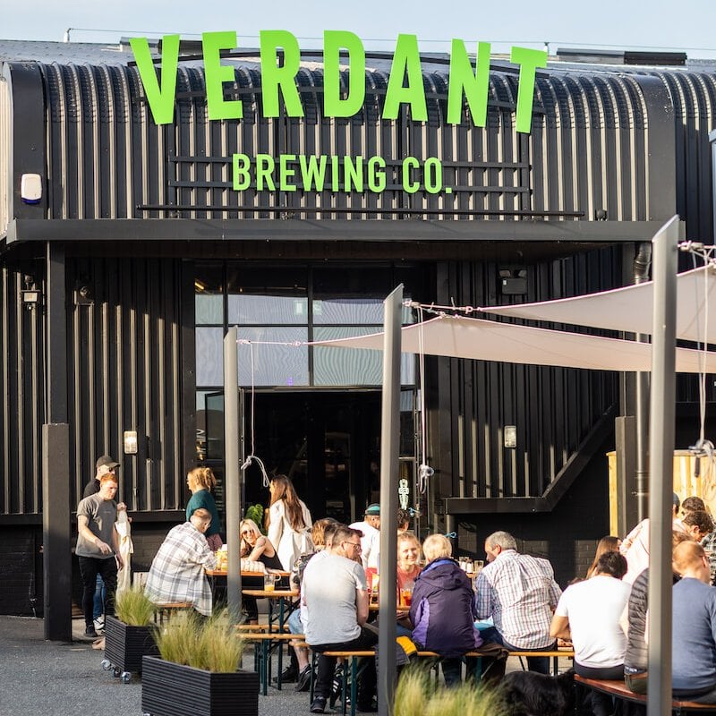People seated on benches outside Verdant Taproom
