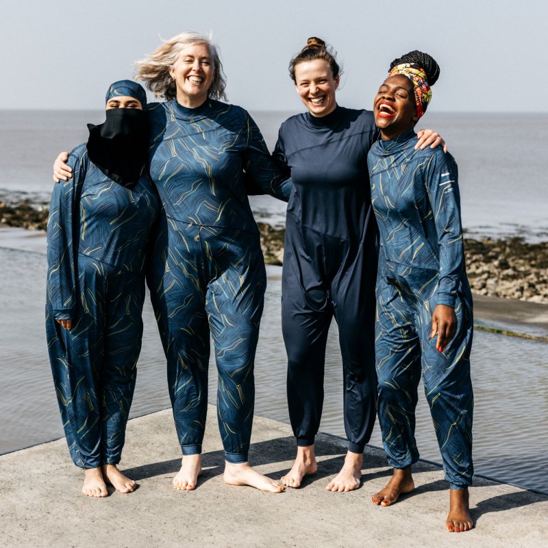 Four diverse women wearing the Finisterre full coverage Seasuit by the sea