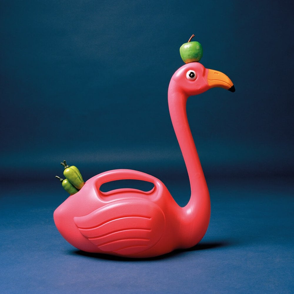 A pink plastic flamingo with a green apple on its head