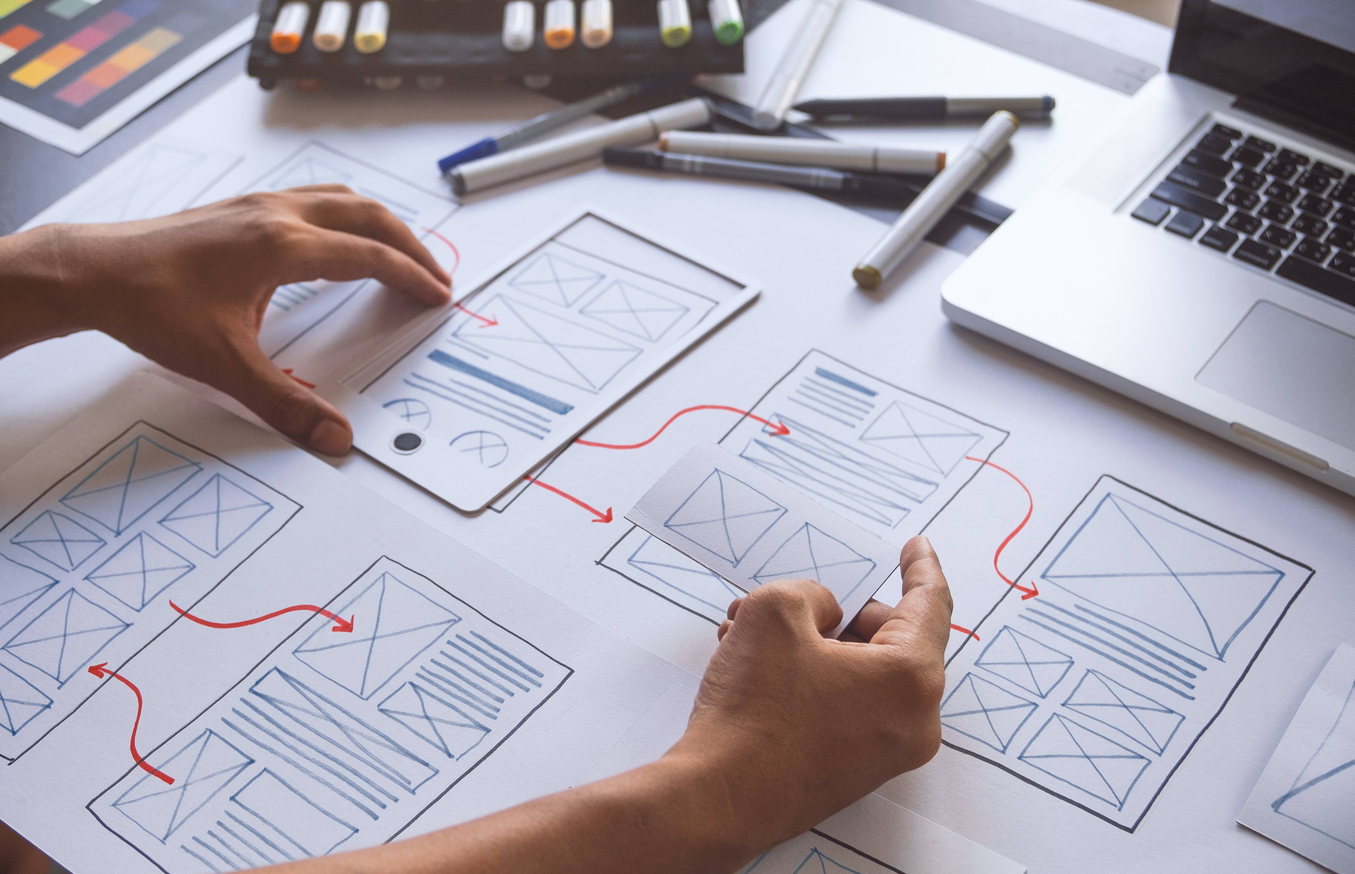 website layout plans on paper with hands and pens