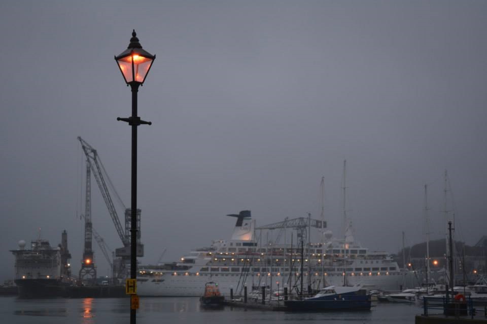 A lamp emits a deep red glow in front of a ferry at night