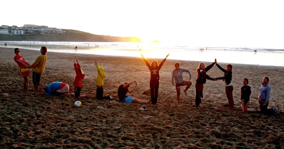 Photo of students on beach spelling out the letters of 'Volleyball' with their bodies