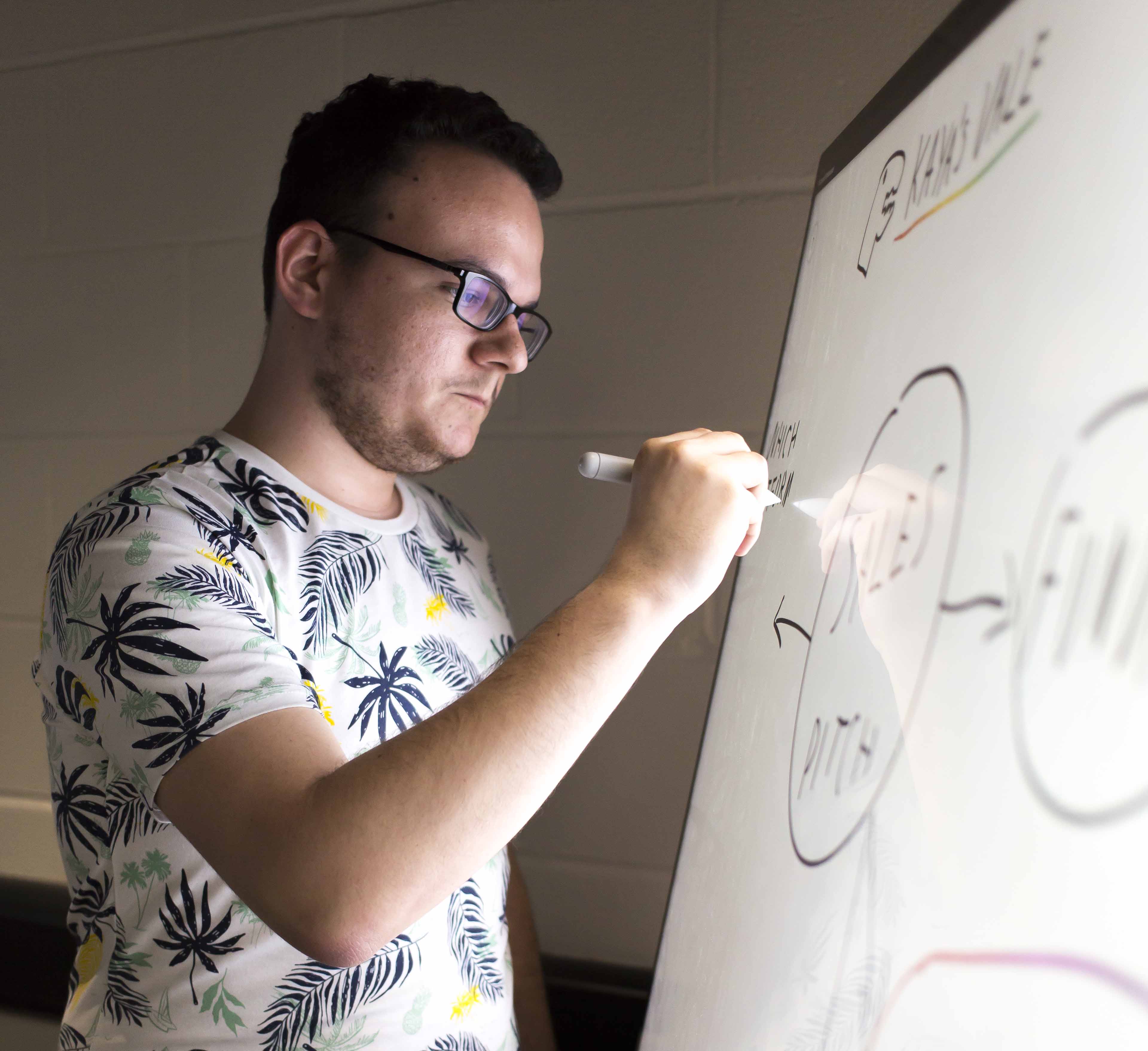 Student writing on a whiteboard, Falmouth University