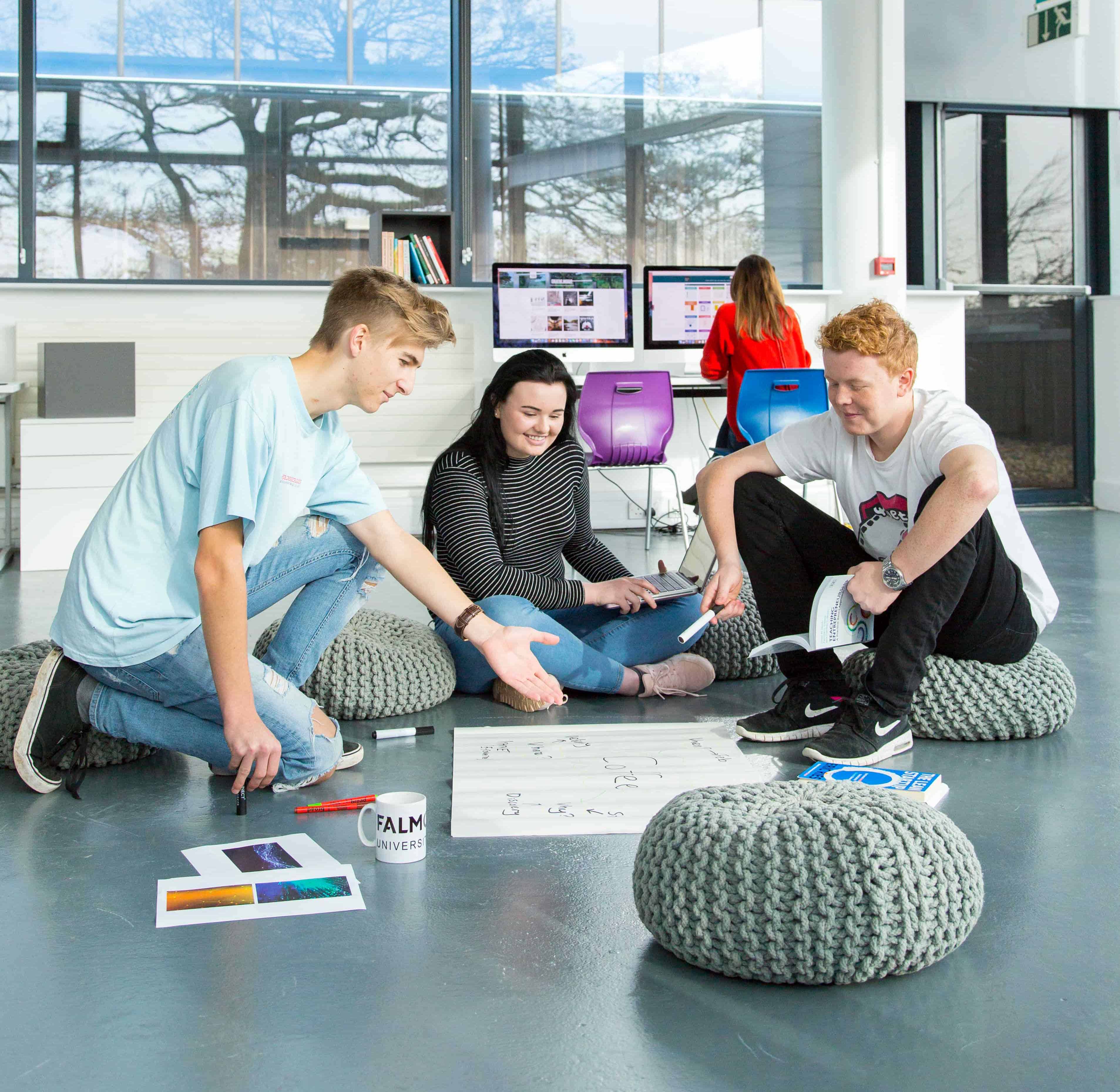 Falmouth University students sitting on beanbags discussing a business concept on the floor
