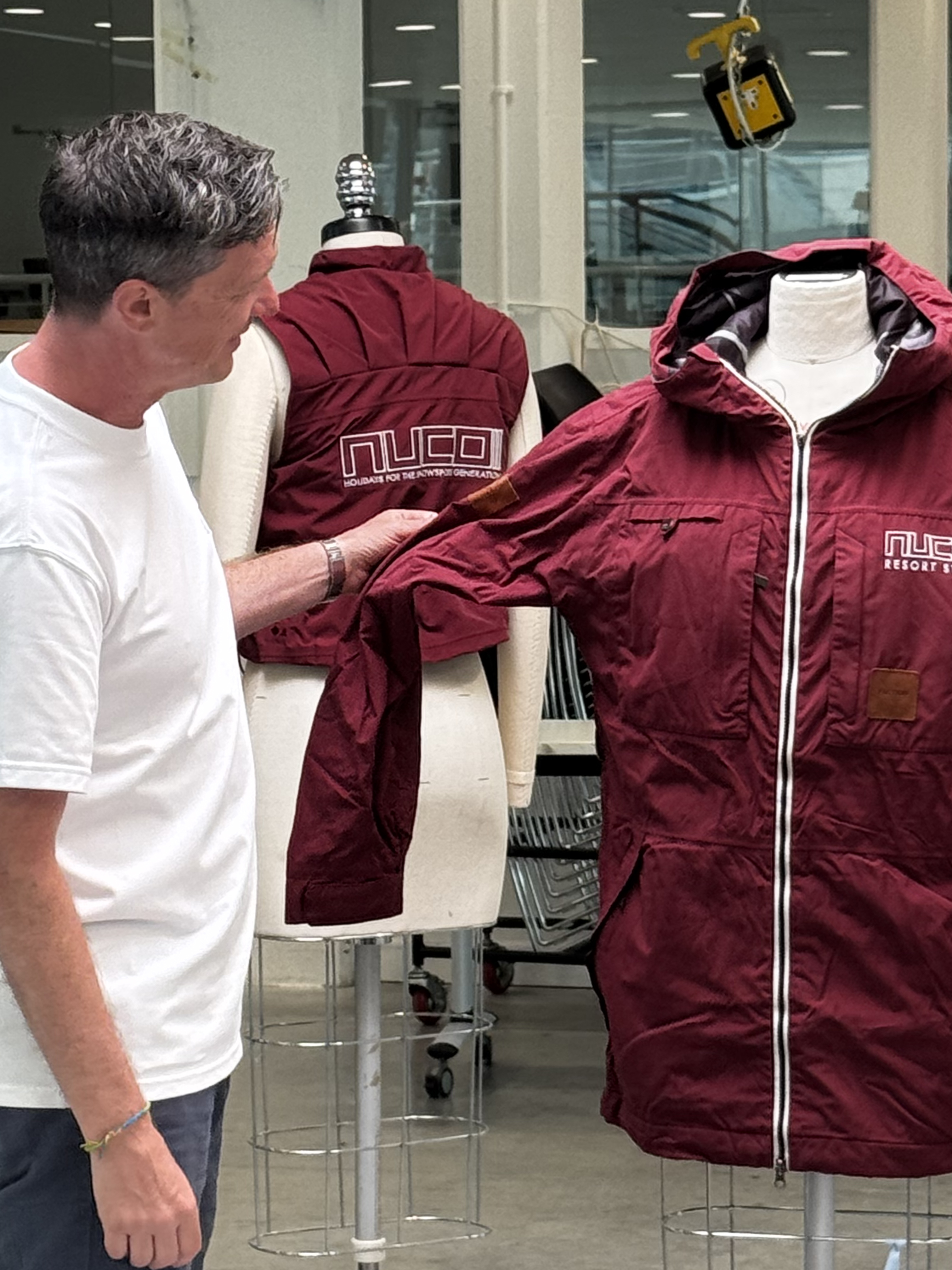 A man stood next to a jacket on a mannequin