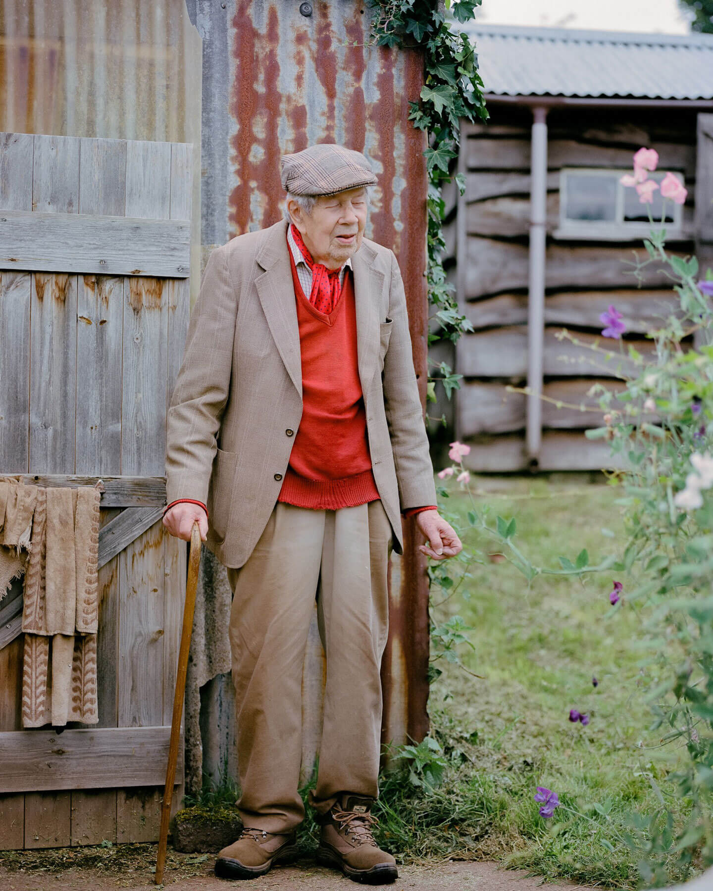 An elderly man standing outside a shed in his garden