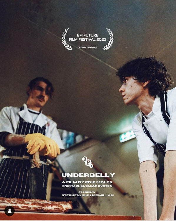 Two butchers looking at each other intensely in a kitched. Text reads: BFI Future Film Festival 2023, Underbelly, A film by Edie Moles and Rachel Clearn Burton, starring Stephen John McMillan