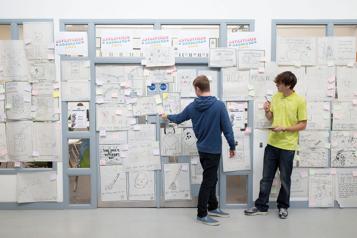 Students standing at a wall full of ideas written on paper