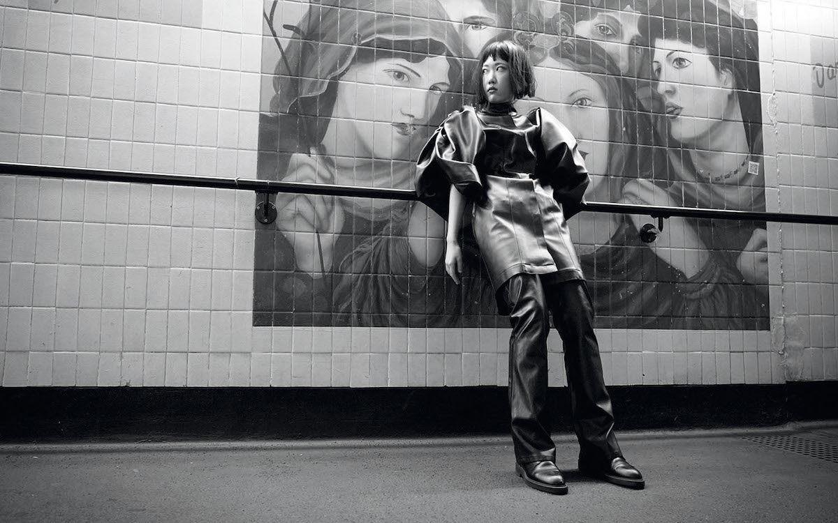 Fashion model posing in front of a mural of pre-raphelite women