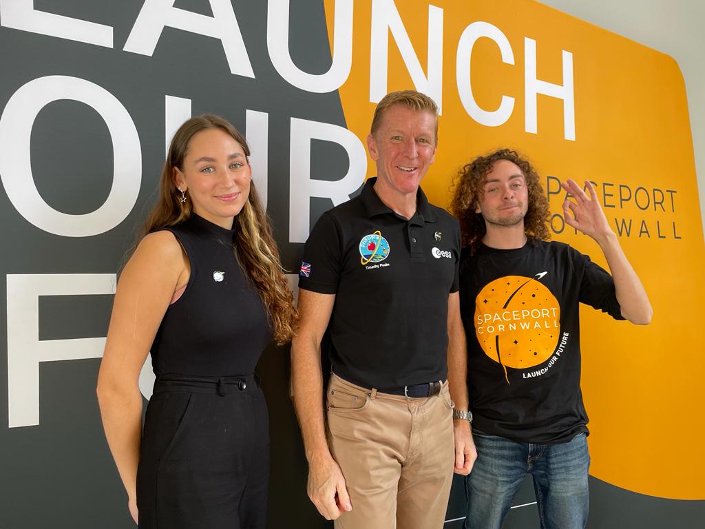 Graduate Rachel Harrison and student Ben Pisacane stand either side of Time Peake in front of backdrop that reads 'Launch our future'.