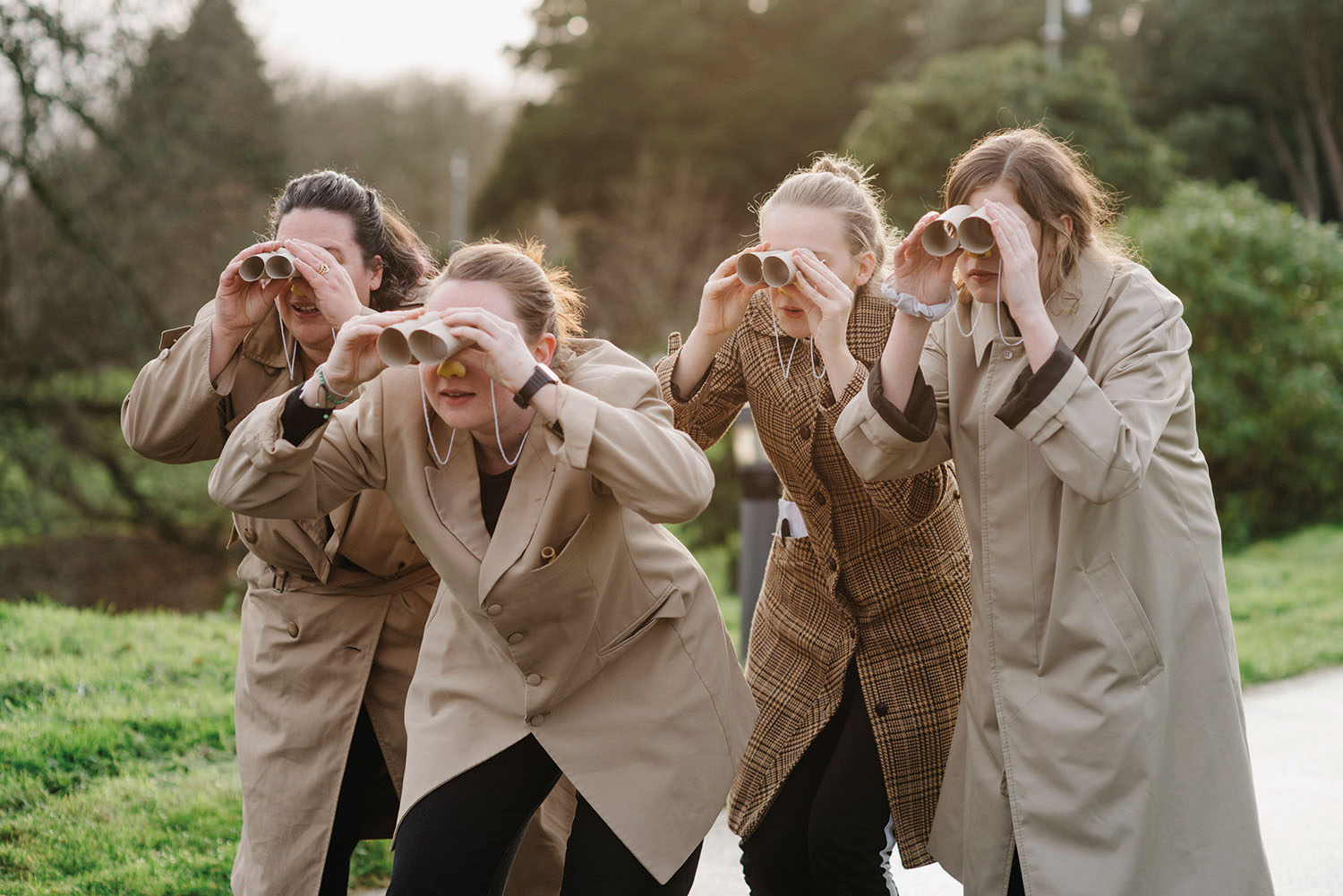 Student actors wear beige jackets and holding toilet rolls as binoculars
