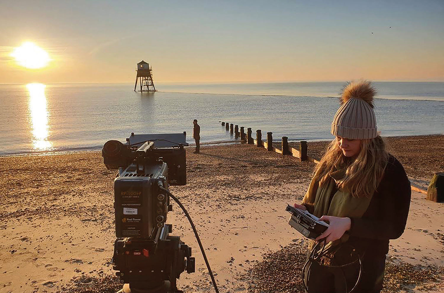 Student with film camera on beach at sunrise