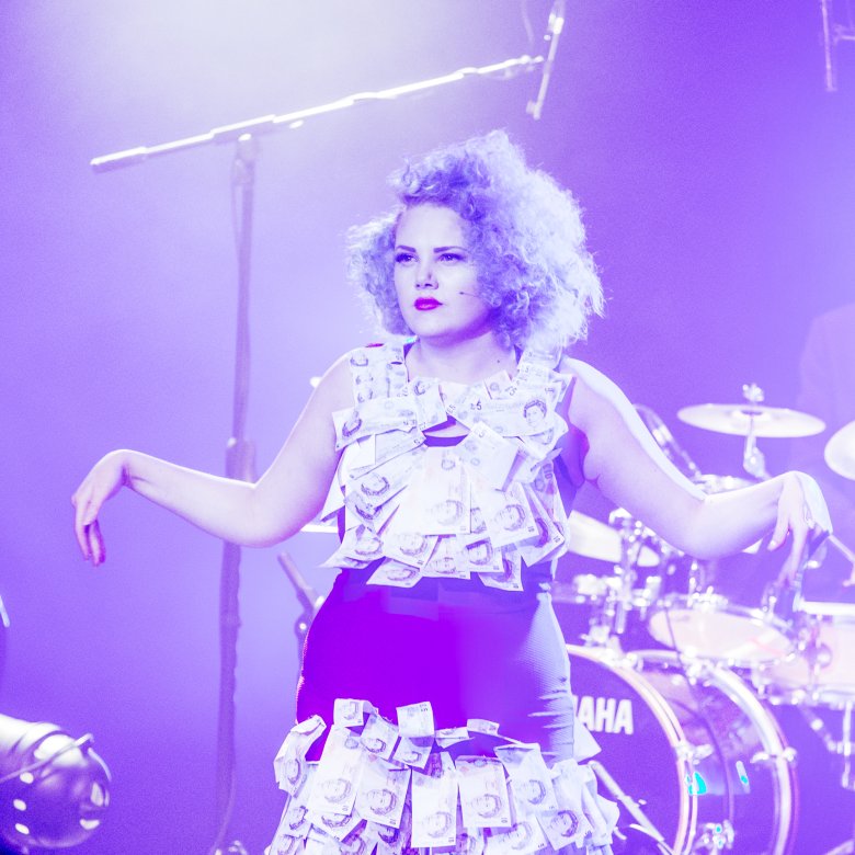 Actor on stage with band lit with purple light.