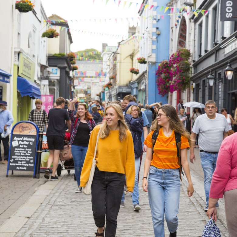 Two students dressed in orange tops walking along Falmouth high street