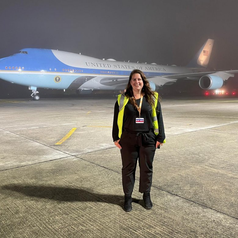 Sustainable Tourism Management wearing a high vis jacket, standing in front of a plane