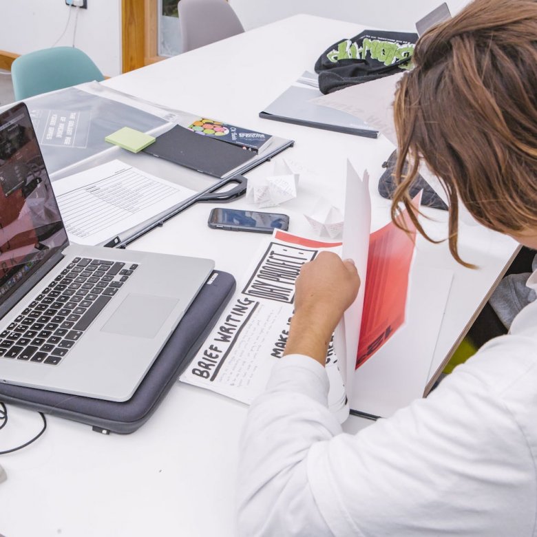 Graphic Design student at a laptop with papers