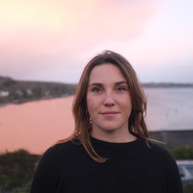 Head shot of graduate Jess Fairlie, with sea view in background