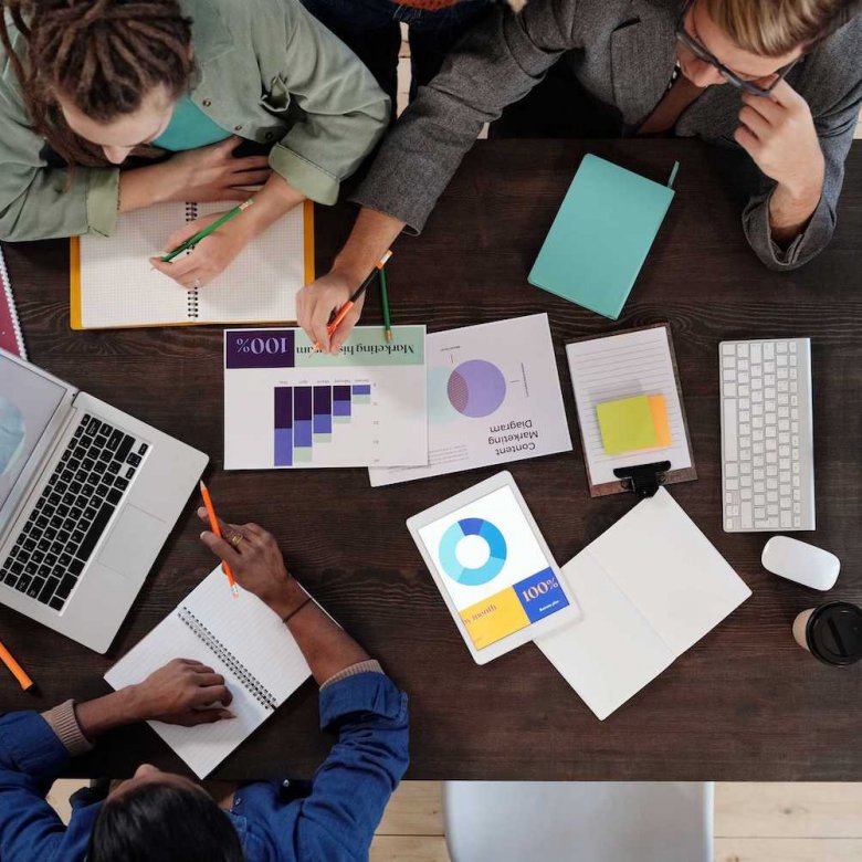 Three people sat at a table with graphs on paper