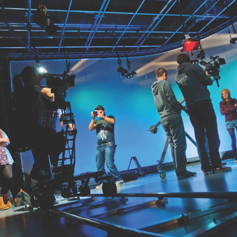 Students working in television studio lit up in blue at Falmouth University