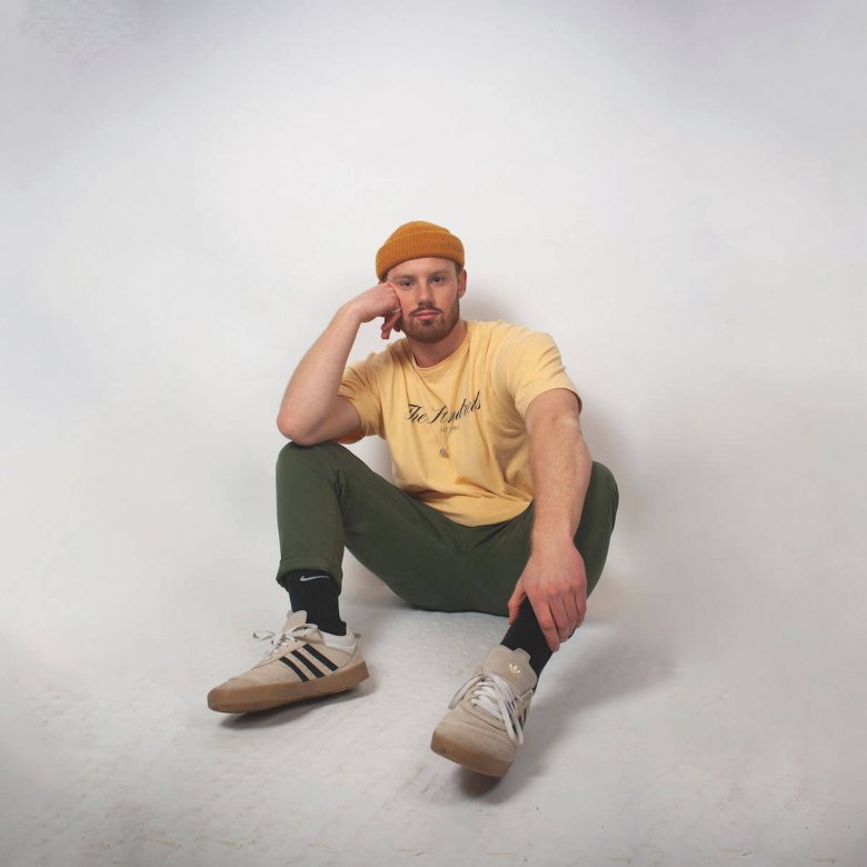 Sustainable Product Design student sitting on the floor wearing an orange hat and yellow tshirt