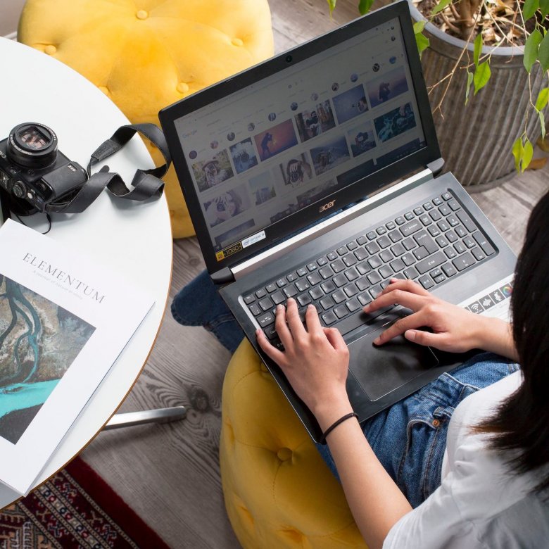 A student working on a laptop next to a white table with a camera and magazine
